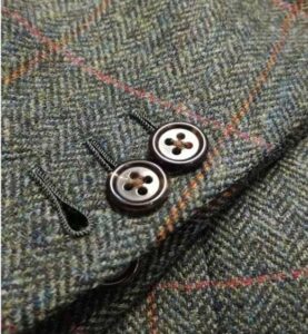 Photo of three handsewn buttonholes on herinbone twill fabric